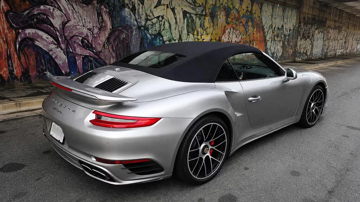 A silver Porsche 911 Turbo cabriolet detailed and parked beside a graffiti wall